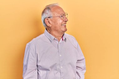 Gri saçlı, zarif tişörtlü ve gözlüklü, yüzünde gülümseme ve doğal ifadeyle yan yana bakan son sınıf öğrencisi. Kendinden emin gülen. 