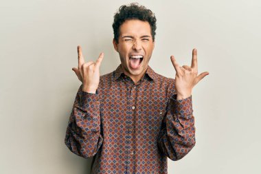 Yakışıklı İspanyol adam gündelik giysiler içinde çılgın bir ifadeyle bağırıyor elleri havada rock sembolü yapıyor. Müzik yıldızı. ağır kavram. 