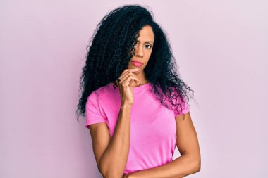 Orta yaşlı Afro-Amerikalı kadın günlük kıyafetler giyiyor kameraya özgüvenli bakıyor kollarını kavuşturup gülümseyerek ve çenesini kaldırarak. Olumlu düşünmek. 