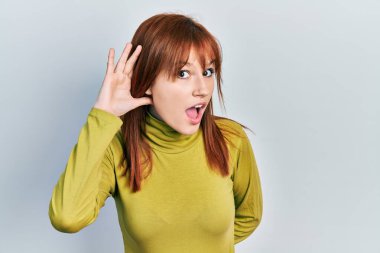 Boğazlı kazak giyen, ağzı kulaklarında gülümseyen, dedikodu ya da dedikoduları dinleyen kızıl saçlı genç bir kadın. Sağırlık kavramı. 