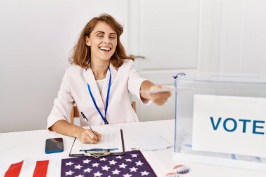 Genç Amerikalı siyasi parti çalışanı seçmen kolejinde oy kullanırken mutlu gülümsüyor.