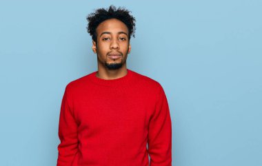 Sakallı, kışlık süveter giyen genç, Afro-Amerikalı bir adam. Yüzünde ciddi bir ifadeyle rahatlamış. Basit ve doğal bir şekilde kameraya bakıyorsun.. 