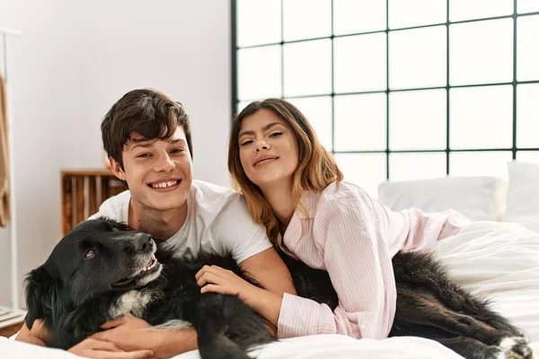 Jovem Casal Caucasiano Sorrindo Feliz Deitado Cama Brincando Com Cão — Fotografia de Stock