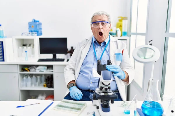 衝撃的な顔で科学研究所で働いているシニア白人男性 懐疑的で皮肉を探して オープン口で驚いて — ストック写真