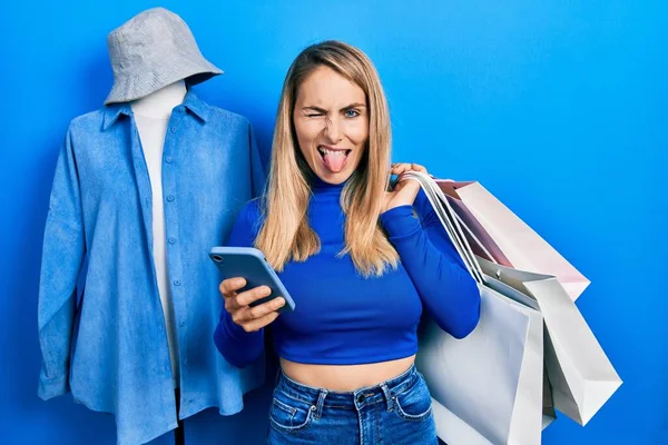Young Caucasian Woman Holding Shopping Bags Smartphone Sticking Tongue Out — 图库照片