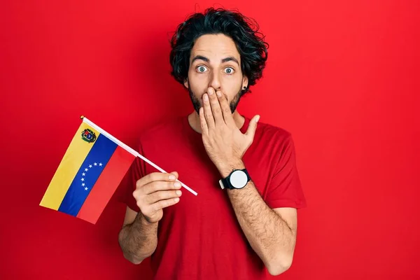 Bonito Hispânico Segurando Bandeira Venezuelana Cobrindo Boca Com Mão Chocado — Fotografia de Stock