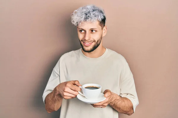 Mladý Hispánec Moderními Barvenými Vlasy Pije Šálek Kávy Usmívá Dívá — Stock fotografie
