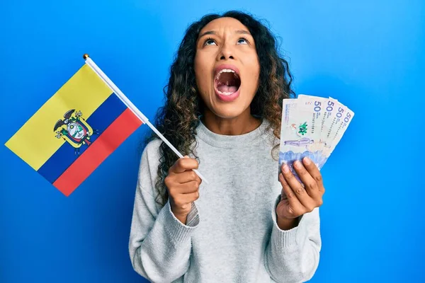 年轻的拉丁女人拿着科洛姆比亚国旗和科洛姆比亚比索钞票 怒气冲冲地尖叫着 怒气冲冲地大叫着 — 图库照片