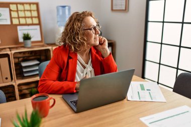 Ofiste çalışan orta yaşlı beyaz iş kadını dizüstü bilgisayar kullanıyor..