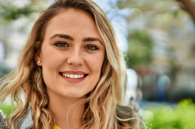 Parkta gülümseyen genç sarışın kadın.