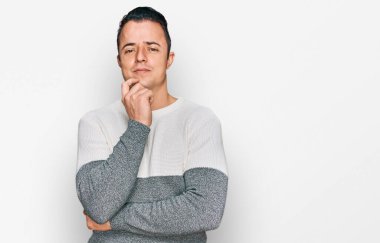 Sıradan bir kazak giyen yakışıklı genç adam kameraya kendinden emin bakıyor kollarını kavuşturmuş ve çenesini kaldırmış bir şekilde gülümsüyor. Olumlu düşünmek. 