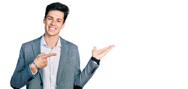 İş kıyafetleri giyen genç İspanyol adam kameraya hayret ediyor ve gülümsüyor.. 