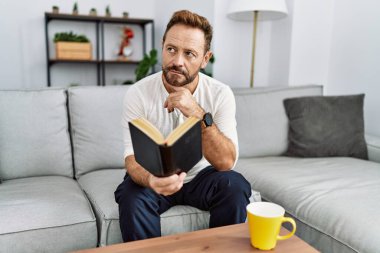 Orta yaşlı İspanyol adam evde kitap okuyor.