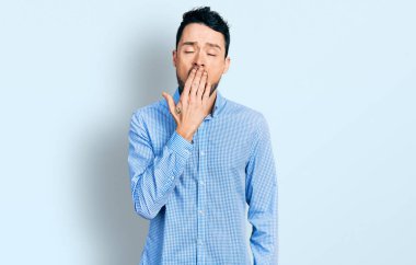 Sıradan iş gömleği giyen İspanyol sakallı adam ağzıyla ağzını kapatmaktan sıkılmış. Huzursuz ve uykulu.. 