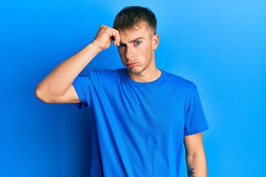 Sıradan mavi tişört giyen genç beyaz adam, alnındaki bir sorun yüzünden endişeli ve stresli. Kriz için endişeli. 