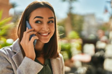 Genç İspanyol kız gülümsüyor. Şehirdeki akıllı telefondan konuşuyor..