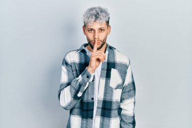 Modern boyalı saçlı, rahat gömlekli, dudakları parmaklı, sessiz olmak isteyen genç bir İspanyol. sessizlik ve gizli konsept. 