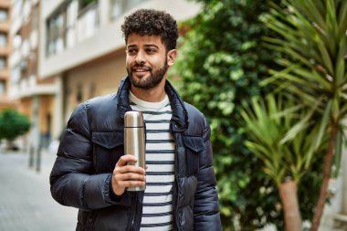 Kasabada elinde kahve termosu tutan genç bir Arap.