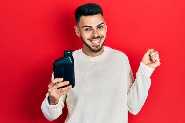 Sakallı, motor yağı şişesi tutan genç İspanyol adam gururla bağırıyor, zaferi kutluyor ve başarıyı kollarını kaldırarak kutluyor. 