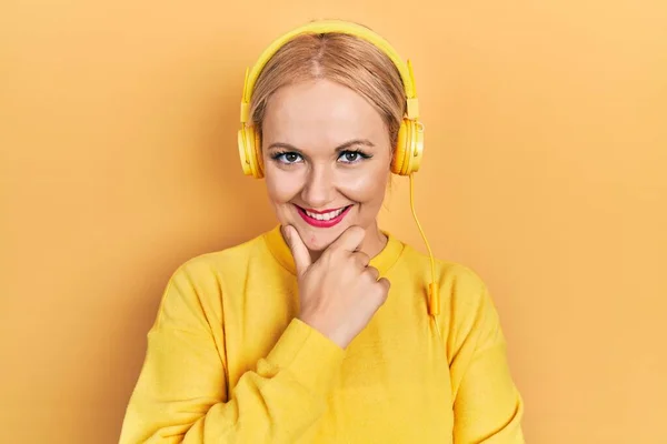 Mujer Rubia Joven Escuchando Música Usando Auriculares Que Miran Confiados —  Fotos de Stock