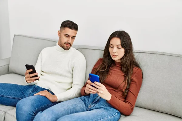 Jong Hispanic Paar Met Behulp Van Smartphone Zitten Bank Thuis — Stockfoto