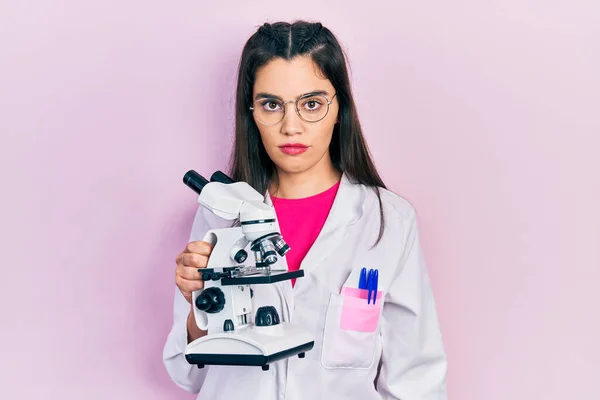 Genç Spanyol Kız Bilim Adamı Üniforması Giyiyor Mikroskop Tutuyor Düşünme — Stok fotoğraf