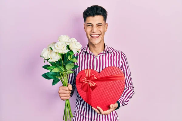 Homem Hispânico Jovem Segurando Presente Aniversário Buquê Flores Piscando Olhando — Fotografia de Stock