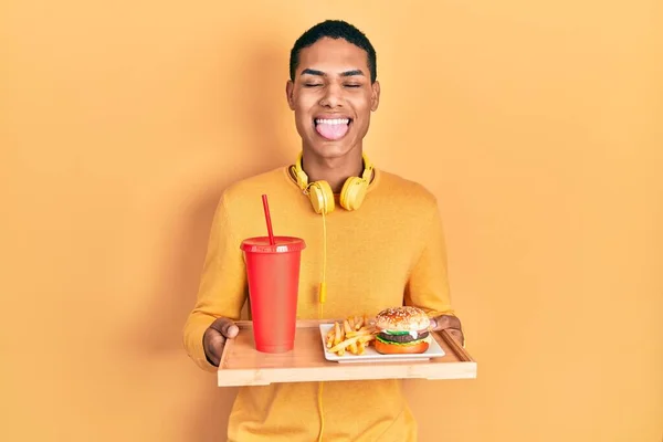 若いですアフリカ系アメリカ人男食べるおいしいです古典的なハンバーガー突き出た舌幸せなで面白い式 — ストック写真