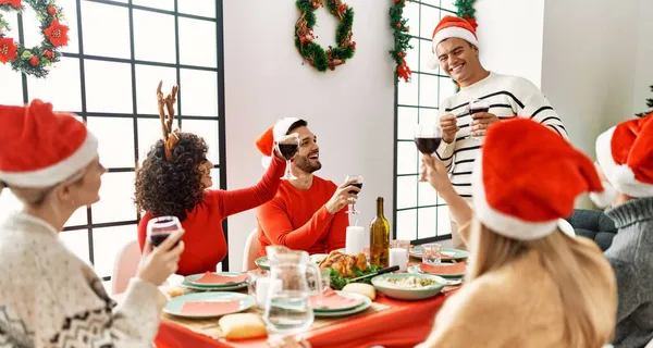 一群年轻人笑着高兴地在家里吃圣诞大餐和祝酒词 — 图库照片