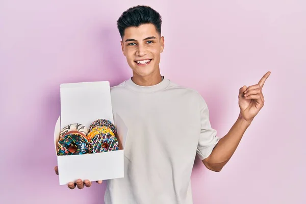 Joven Hombre Hispano Sosteniendo Caja Sabrosas Rosquillas Coloridas Sonriendo Feliz —  Fotos de Stock