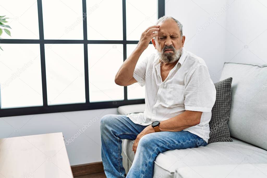 Senior grey-haired man with headache at home