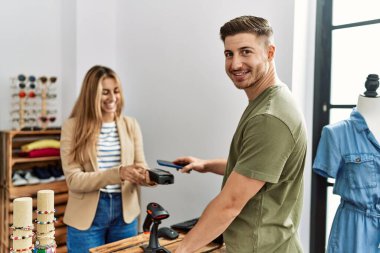 Genç İspanyol müşteri mağazada akıllı telefon kullanarak dükkan sahibine ödeme yapıyor..