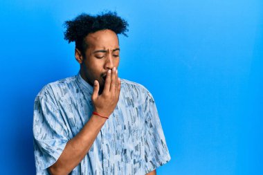 Sakallı, sıradan kıyafetler giyen, esnemekten sıkılmış, ağzı eliyle kapatan Afrikalı genç bir Amerikalı. Huzursuz ve uykulu.. 