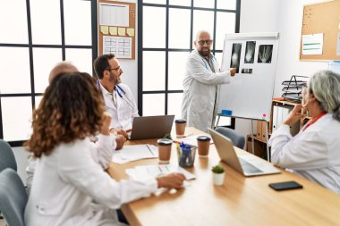 Bir grup orta yaşlı doktor klinikteki bir tıbbi toplantıda tartışıyorlar..