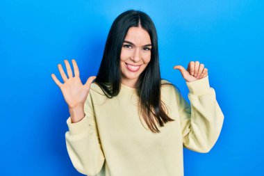 Genç esmer kadın, günlük eşofman altı numarayı gösterip gösterirken kendinden emin ve mutlu gülümsüyor.. 