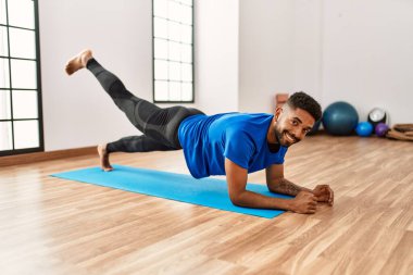 Yakışıklı İspanyol adam egzersiz yapıyor ve yoga minderinde geriniyor. Spor salonunda esneklik ve antrenman yapıyor.