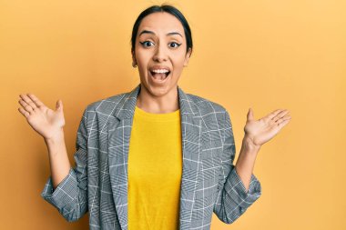 İş kıyafetleri giyen genç İspanyol kız zaferi mutlu bir gülümsemeyle ve kazanan yüz ifadesiyle kutluyor. 