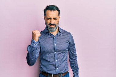 Orta yaşlı, sakallı, gri saçlı, iş kıyafetleri giyen öfkeli ve kızgın bir şekilde yumruğunu kaldıran öfkeli bir adam. öfke ve agresif konsept. 