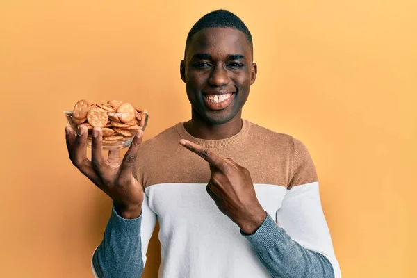 Joven Afroamericano Hombre Sosteniendo Tazón Con Galletas Saladas Sonriendo Feliz — Foto de Stock