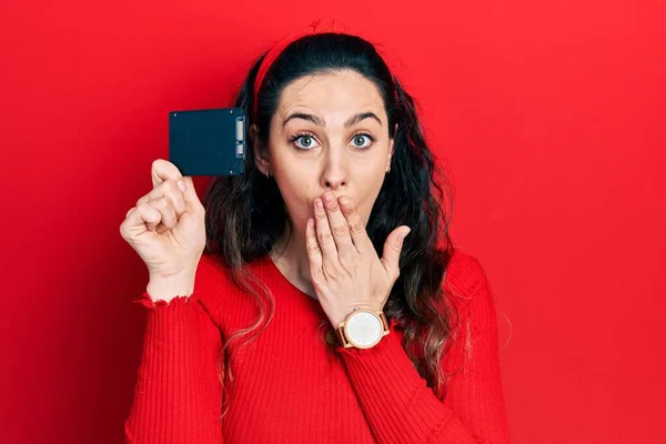 Young Hispanic Woman Holding Ssd Memory Covering Mouth Hand Shocked — Stock Photo, Image