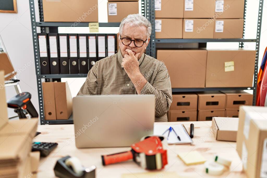 Senior caucasian man working at small business ecommerce with laptop looking confident at the camera with smile with crossed arms and hand raised on chin. thinking positive. 