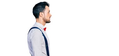 Sakallı, hippi görünümlü, papyon takan, pantolon askısı takan, rahat profil pozu veren, kendine güveni tam bir gülümseme takınan İspanyol bir adam.. 