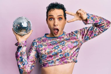 Parlak disko topunu tutan yakışıklı adam şaşkınlık ve şaşkınlık dolu ifade, korku ve heyecan dolu yüz ifadesiyle şok oldu.. 