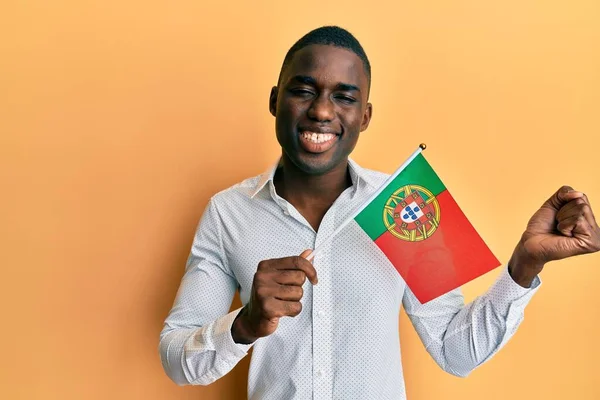 年轻的非洲裔美国人举着葡萄牙国旗高呼自豪 高举双臂庆祝胜利和成功 — 图库照片