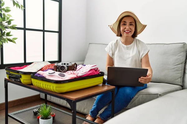 Medelålders Latinamerikansk Kvinna Packar För Semester Med Bärbar Dator Hemma — Stockfoto