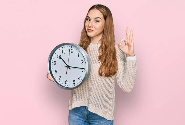 Young Blonde Woman Holding Big Clock Doing Sign Fingers Smiling — Foto Stock