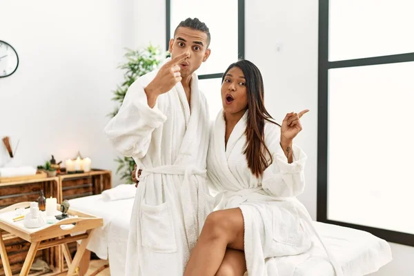 Young Latin Couple Wearing Towel Standing Beauty Center Surprised Pointing — Stockfoto