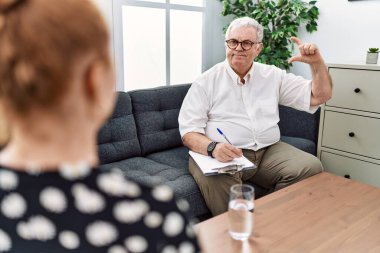 Danışma ofisindeki kıdemli psikolog gülümseyen ve el hareketleriyle hareket eden parmaklarıyla işaret yapan ve kameraya bakan. ölçüm kavramı. 