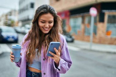 Genç İspanyol kadın akıllı telefon kullanıyor. Şehirde kahve içiyor..