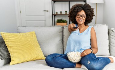 Genç Afro-Amerikan kadın gülümsüyor. Evde film izlerken kendine güveniyor.